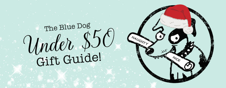 Festive illustration of a cartoon dog wearing a Santa hat, holding scrolls labeled "Naughty" and "Nice." Text reads "The Blue Dog Under $50 Gift Guide!" Background with snowflake pattern.