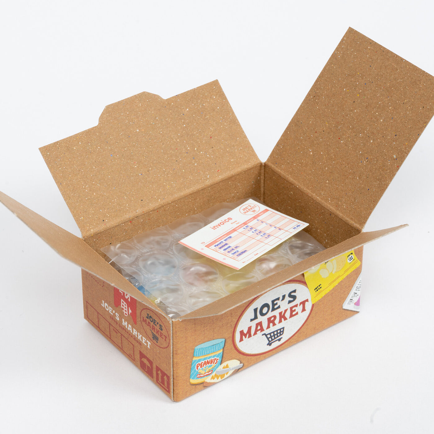 A cardboard box labeled "Japanese Mini Sticker Box Joe's Market" by Blue Dog Posters is open, showing a plastic bag of colorful stickers and a small paper insert with text and a chart inside.