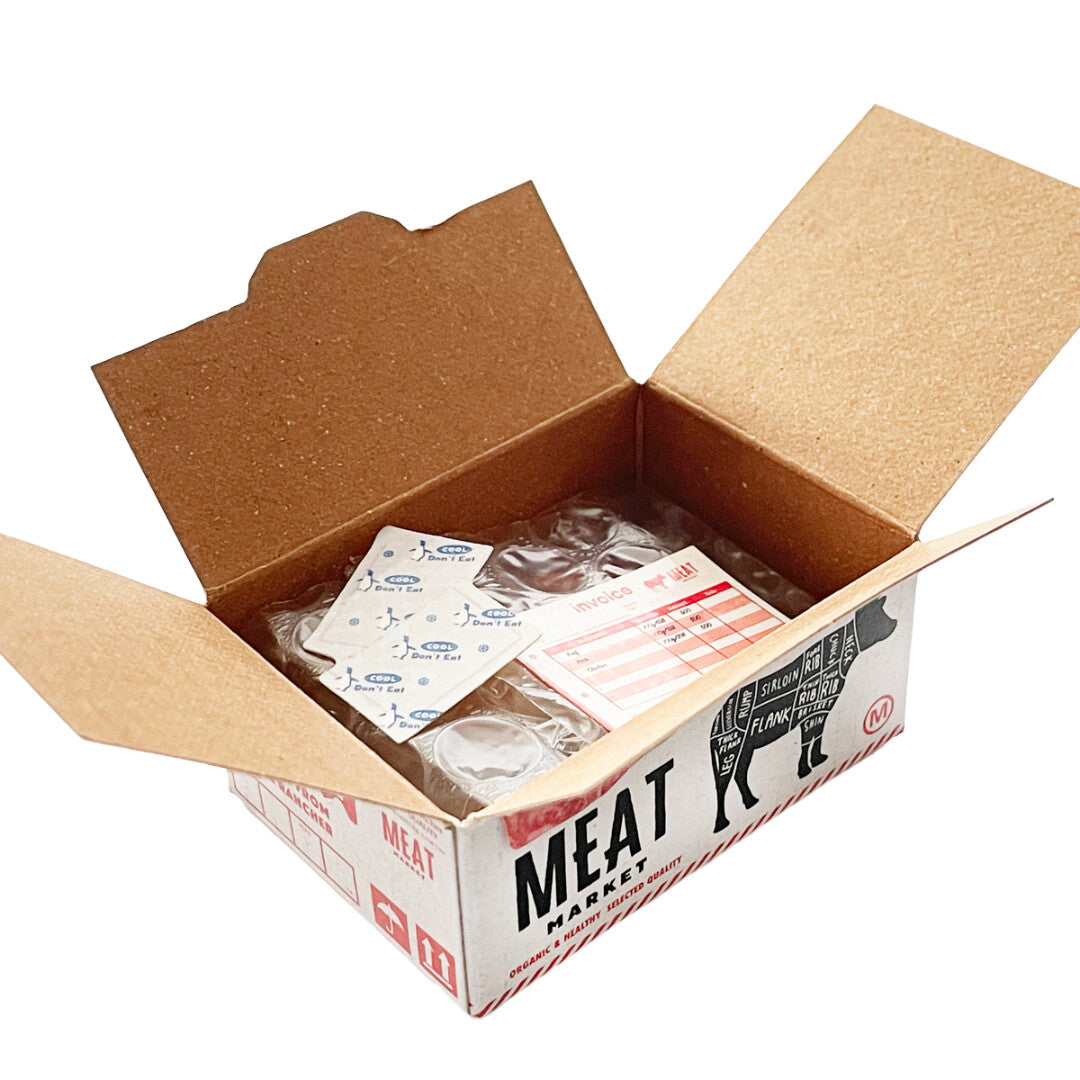 An open cardboard box labeled "Japanese Mini Sticker Box Meat" by Blue Dog Posters features meat-themed graphics, a label with meat cut diagrams, packaged stickers, and a moisture absorber, with the flaps opened for display.