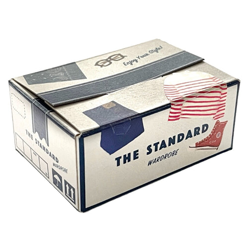 A rectangular box called "Japanese Mini Sticker Box The Standard" by Blue Dog Posters, featuring postal graphics, a red-and-white stripe, and an illustration of a shirt with hanger.