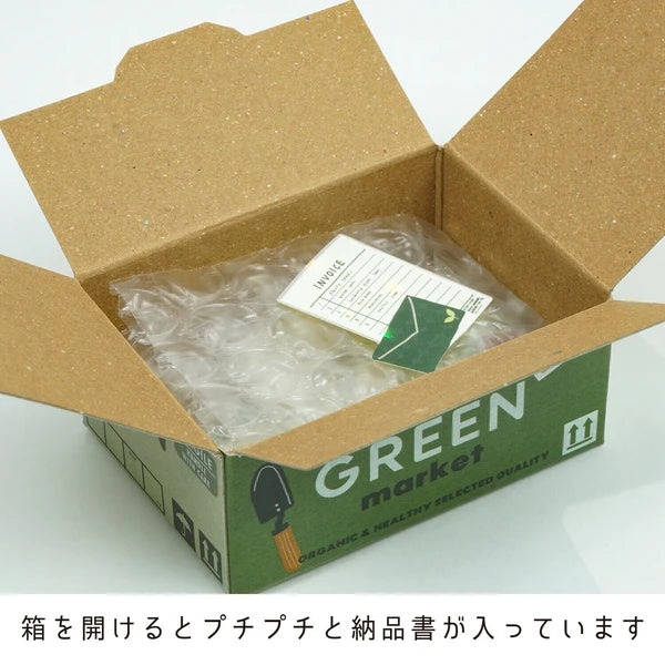 An open "Japanese Mini Sticker Box Green" by Blue Dog Posters holds bubble wrap, a packing slip, and mini stickers. The box is labeled "GREEN market," with Japanese text below detailing the contents.