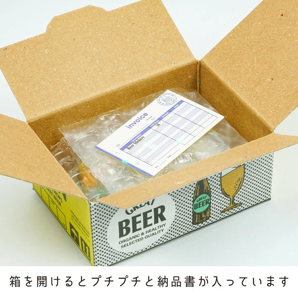 An open box labeled "Japanese Mini Sticker Box Beer" from Blue Dog Posters contains bubble wrap, an invoice, and cute stickers. Japanese text at the bottom describes the contents.