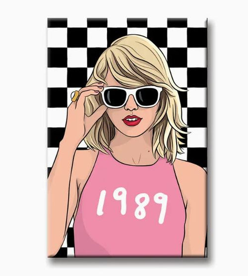 A stylized cartoon woman with blonde hair, dark sunglasses, and a pink tank top emblazoned with "1989" is featured holding the sunglasses with one hand against a black and white checkered pattern. This design by Blue Dog Posters, made in the USA, is perfect for any fridge as the Taylor Swift 1989 Magnet.