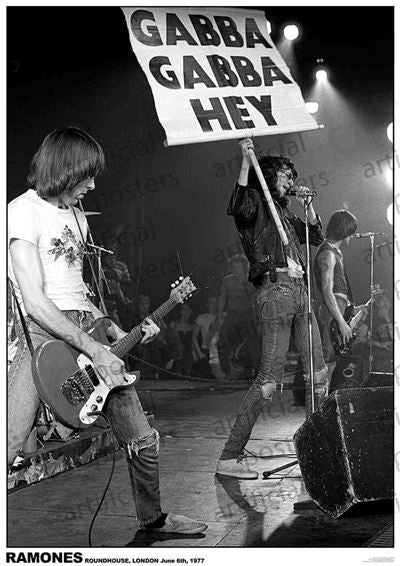 Capture the essence of a legendary 1977 performance with this black and white photo from the Roundhouse in London, featuring the iconic band, Ramones. Witness a guitarist in action while the vocalist holds up the famous "Gabba Gabba Hey" sign, with another band member visible in the background. This Ramones - Gabba gabba Hey poster by MUS 337 is printed on Premium Gloss Paper for enduring quality and makes a perfect addition to your music collection.