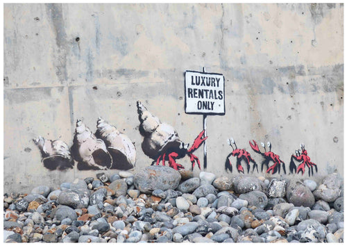 The Banksy Cromer Crabs mural portrays a line of hermit crabs carrying luxury items, including large conch shells, as they march past a sign reading "Luxury Rentals Only" on a weathered concrete wall. The ground is strewn with pebbles. This striking piece from Brand Y is available as A3 posters printed on 250gsm satin paper.