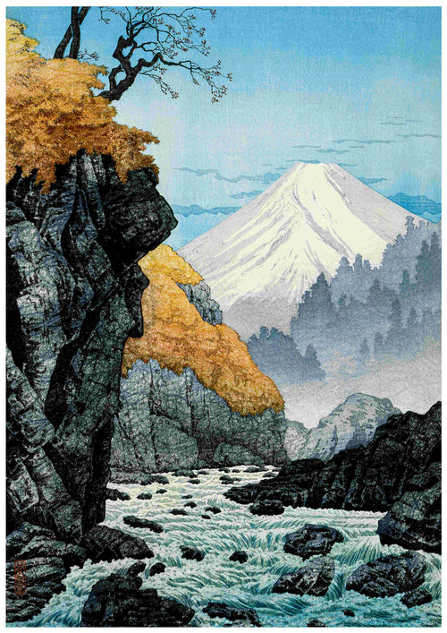 The Hiroaki Takahashi - Foot of Mount Ashitaka by A3 depicts a serene landscape with a rushing river flowing through rocky terrain, autumn-colored foliage, and a lone tree perched on a cliff. In the background, the majestic snow-capped Mount Ashitaka stands tall under a clear blue sky, with mist enveloping distant trees—all meticulously captured on high-quality 250gsm Satin Paper.