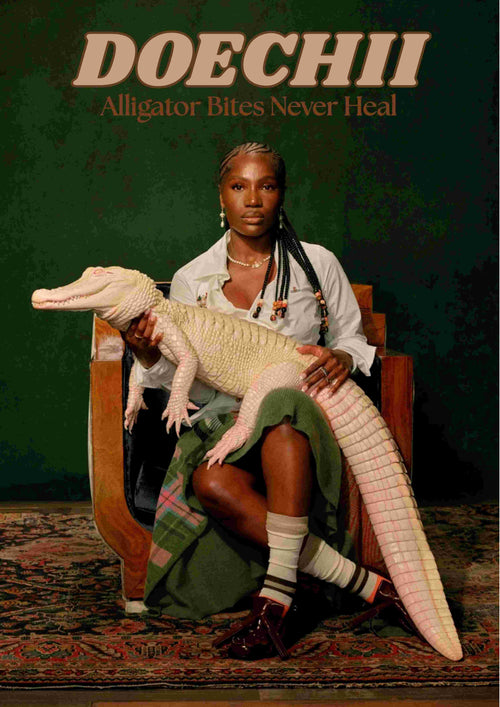 A woman in a white shirt and plaid skirt sits on a wooden chair holding a pale alligator. Above her is the text, "DOECHII Alligator Bites Never Heal." This A3 satin paper music poster by Blue Dog Posters features a dark green background.