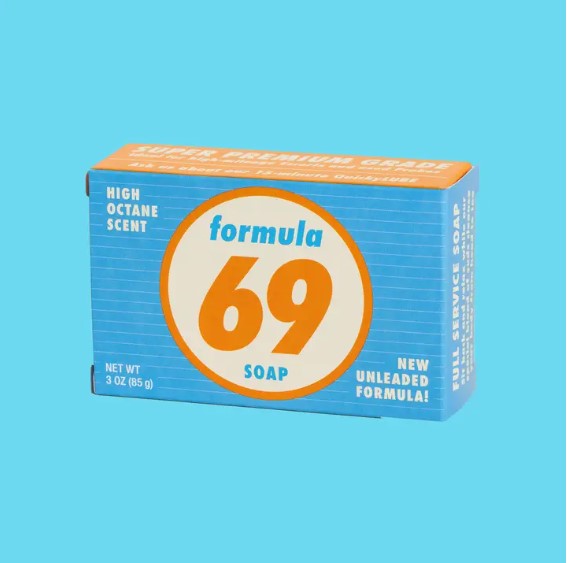 A rectangular box of Formula 69 Triple Milled Boxed Bar Soap by Blue Dog Posters, featuring a vintage-style colorful design with orange and blue hues. The front displays text such as "High Octane Scent," "Net WT 3 OZ (85 g)," and "New Unleaded Formula!" against a light blue background. Perfect for personal hygiene, this Vermont-made triple-milled soap is an ideal choice.