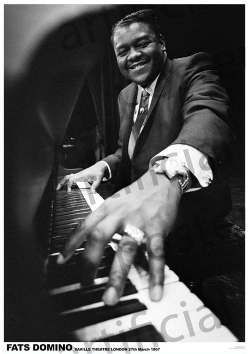 Black and white photo of a man joyfully playing the piano. He is dressed in a suit and tie, with rings on his fingers and a watch on his wrist. Text at the bottom reads: "Fats Domino, Saville Theatre London, 27th March 1967." Perfect for any Music Collection or as a Rock and Roll Poster printed on premium 150gsm gloss paper. Product Name: Fats Domino London 1967 by Brand: MUS 144.