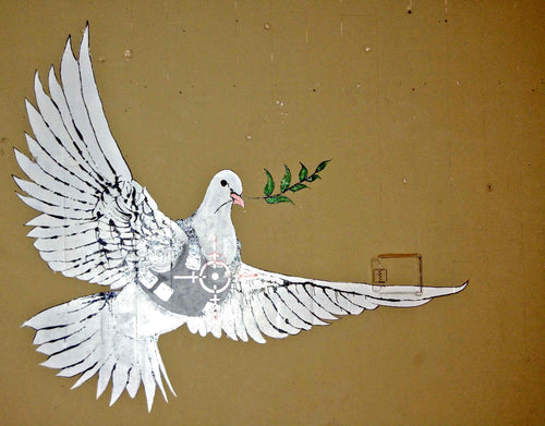 A mural of a white dove in flight carrying an olive branch in its beak and depicted wearing a bulletproof vest with a target symbol on it is painted against a beige wall. The "Banksy Peace Dove in Armoured Vest" by Brand Y captures this powerful image on high-quality 250gsm Satin Paper as an A3 poster.