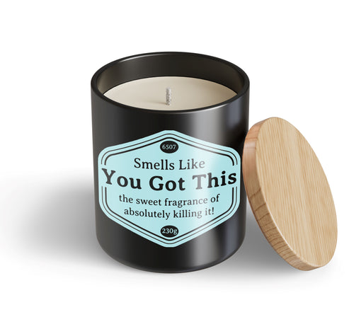 A black jar candle from Blue Dog Posters, "You Got This Candle Hustle & Co," with a wooden lid. The label reads: "Smells Like You Got This—the sweet fragrance of absolutely killing it!.