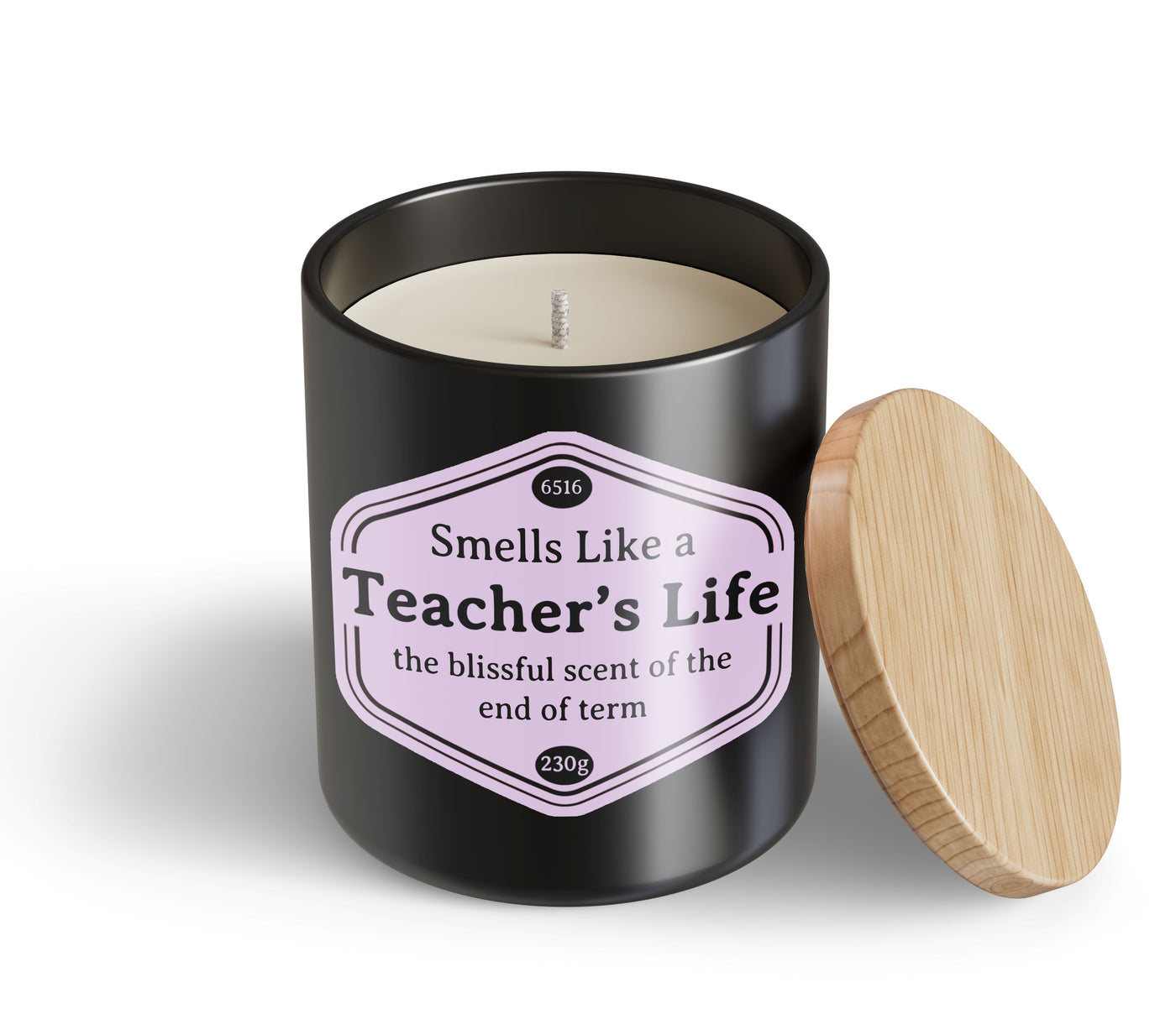 A black Teachers Life Candle Hustle & Co by Blue Dog Posters, unused, with a wooden lid resting beside it and labeled “Smells Like a Teacher’s Life: the blissful scent of the end of term.”.