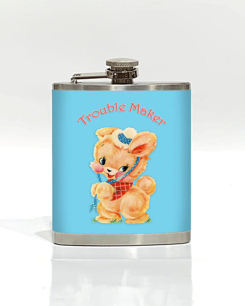 The Trouble Maker Hip Flask by Blue Dog Posters is a stainless steel flask adorned with a light blue label. The label features a vintage-style illustration of an adorable, anthropomorphic bunny dressed in a red checkered bib and a polka-dot bonnet. Above the bunny, "Trouble Maker" is written in a playful font, making it one of the coolest gifts around.
