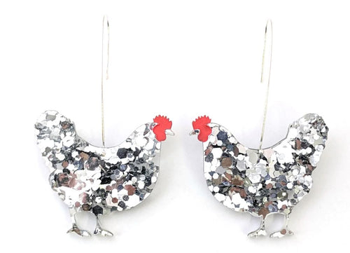 Silver chicken-shaped earrings with red combs are adorned with a glittery, speckled design. These charming Hen Glitter Dangle Earrings Silver by Blue Dog Posters feature a hooked wire for attachment, making them perfect handmade jewellery pieces.