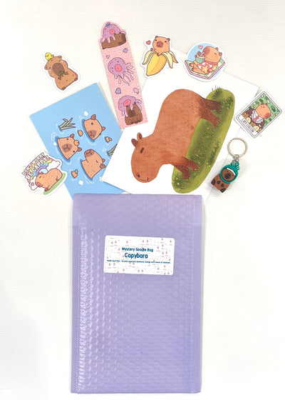 The Mystery Goodie Bag - Capybara by Blue Dog Posters features a purple bubble mailer filled with capybara-themed stickers, bookmarks, a postcard, and a mini keychain—an ideal surprise for any capybara enthusiast.