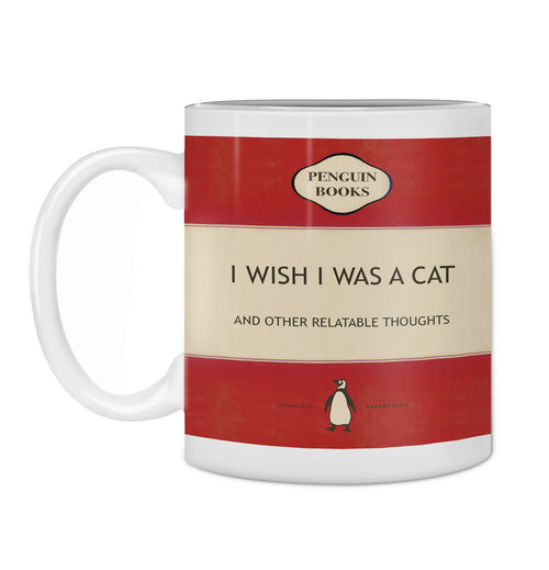 Introducing our Hustle & Co Book Mug - Wish I Was a Cat by Blue Dog Posters! This white mug from the Homewares Collection features a charming design inspired by a Penguin Books cover. The title on the mug reads "I WISH I WAS A CAT AND OTHER RELATABLE THOUGHTS." It showcases a striking red background with a cream-colored center, complete with the iconic Penguin Books logo. Plus, it's dishwasher safe for your convenience.