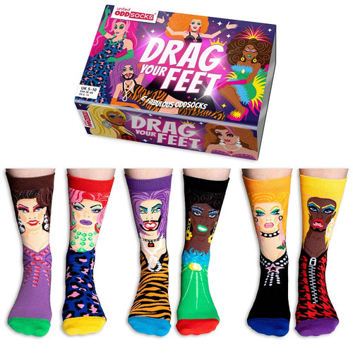 A vibrant set of mismatched socks showcased in a "United Oddsocks Gift Box - Drag Your Feet" from Blue Dog Posters. Every sock features a distinct drag queen character adorned with bright patterns and hues, including designs in purple, pink, green, yellow, and black.