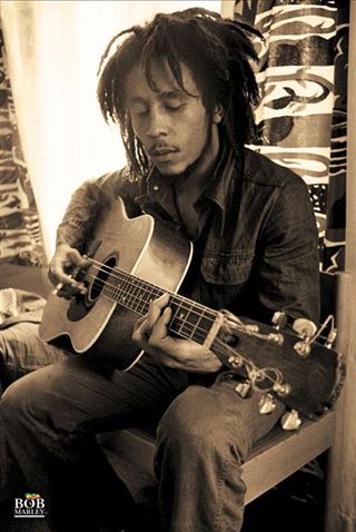 A man with dreadlocks sits, playing a Bob Marley Guitar by MUS 157. Donning a denim shirt and radiating a relaxed vibe, he's framed by patterned curtains with bold designs. The image, reminiscent of a rock poster, sports a vintage, sepia-toned filter.