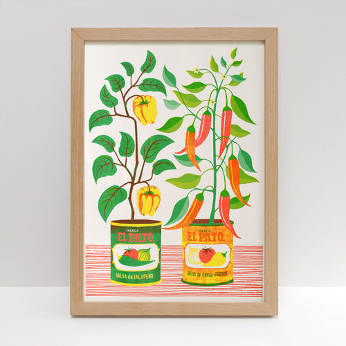 This vibrant A3 Risograph print by Blue Dog Posters, entitled "Chilli Peppers Riso Print" by Printer Johnson, features a framed illustration of two plants growing from cans labeled "El Pato." One plant bears yellow fruits while the other sports red chili peppers. The eco-friendly soy-based inks depict labels reading "Salsa de Jalapeño" and "Salsa de Chile Fresco," all set against a white background accented with red lines.