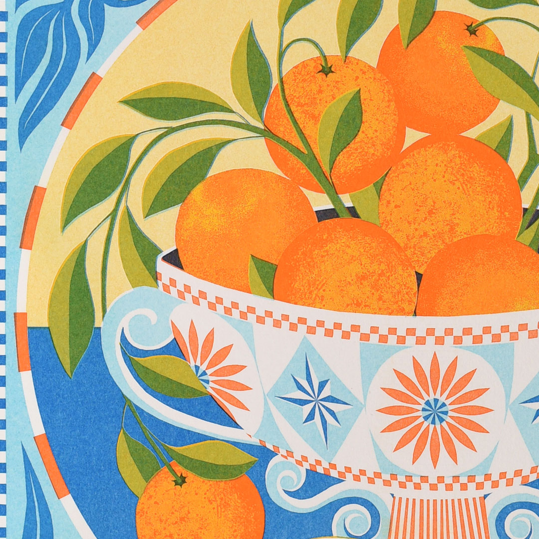 The "Orange Bowl Riso Print" by Printer Johnson, available from Blue Dog Posters, features a vibrant display of oranges nestled in an ornate bowl. The scene is adorned with geometric floral patterns in shades of blue, orange, and white. Green leaves accentuate the oranges, while a decorative border frames the artwork. This print is created using eco-friendly soy-based inks from a specialist Risograph studio.