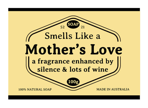 The yellow label on Blue Dog Posters' "Hustle and Co Soap - Mothers Love" reads: "Smells Like a Mother’s Love—a fragrance enhanced by silence & lots of wine," with black borders, "100% natural soap," "Made in Australia," and "100g.