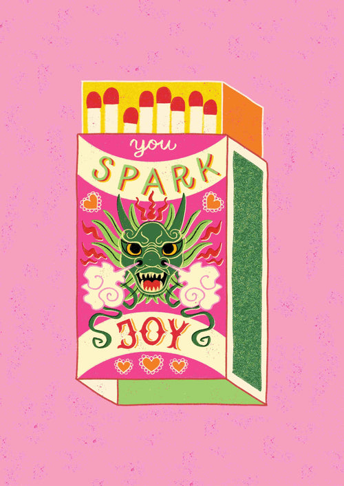 The "You Spark Joy by Miriam Giudici" art print from Blue Dog Posters features a colorful illustration of a matchbox with a green dragon and flames set against a pink background. The box displays the phrase “You Spark Joy” at the top and bottom. As part of the Featured Artists Collection, this design by Miriam Giudici includes hearts and ornate patterns, giving it a vibrant and whimsical look perfect for an art print.