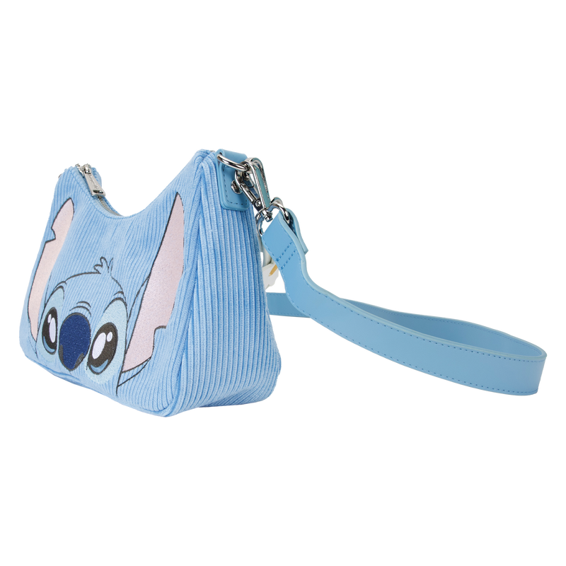 A small, blue Lilo & Stitch Springtime Daisy Crossbody from Blue Dog Posters features a depiction of the animated character's face on the front, complete with large ears and wide eyes. This Disney product is crafted from vegan leather and includes a wrist strap, ribbed texture, and a zipper closure at the top.