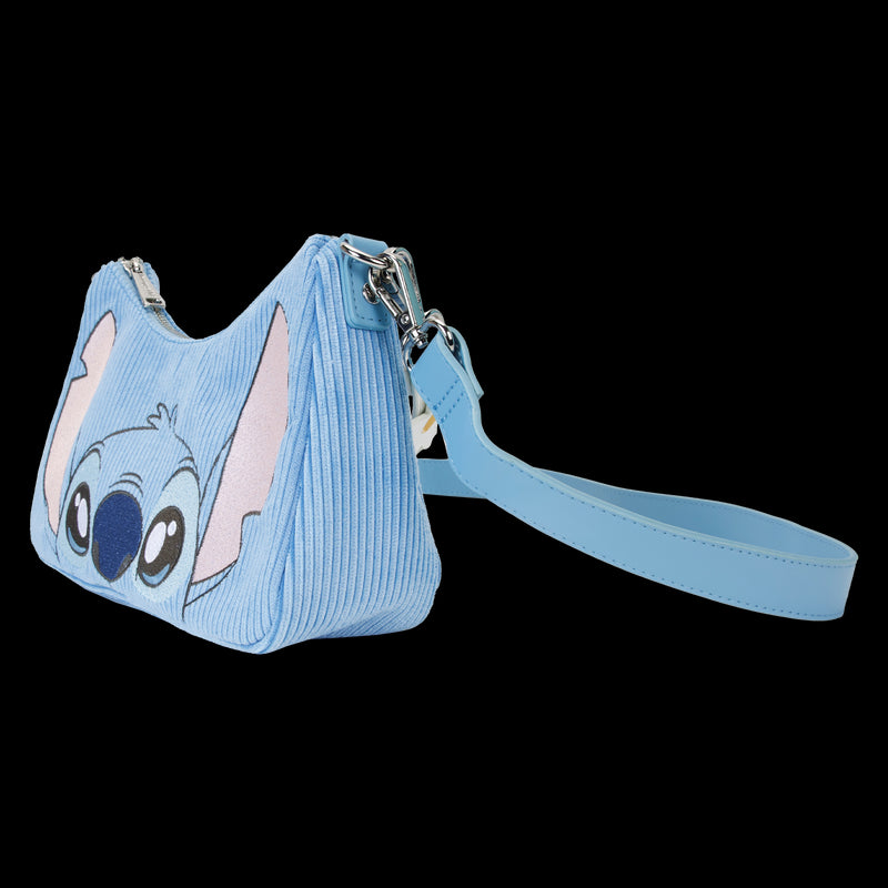 A small, blue Lilo & Stitch Springtime Daisy Crossbody from Blue Dog Posters features a depiction of the animated character's face on the front, complete with large ears and wide eyes. This Disney product is crafted from vegan leather and includes a wrist strap, ribbed texture, and a zipper closure at the top.