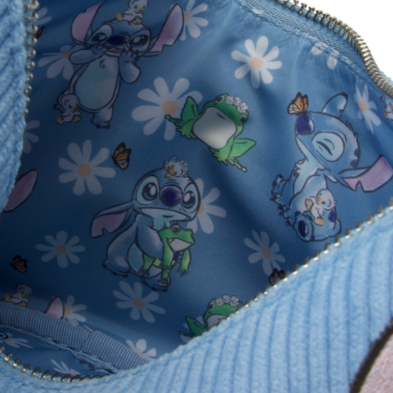 The interior of the Lilo & Stitch Springtime Daisy Crossbody from Blue Dog Posters features a whimsical pattern with images of the animated character in different poses. Stitch interacts with a frog, butterflies, and small creatures against a backdrop of white flowers on blue vegan leather—truly a delightful Disney product.