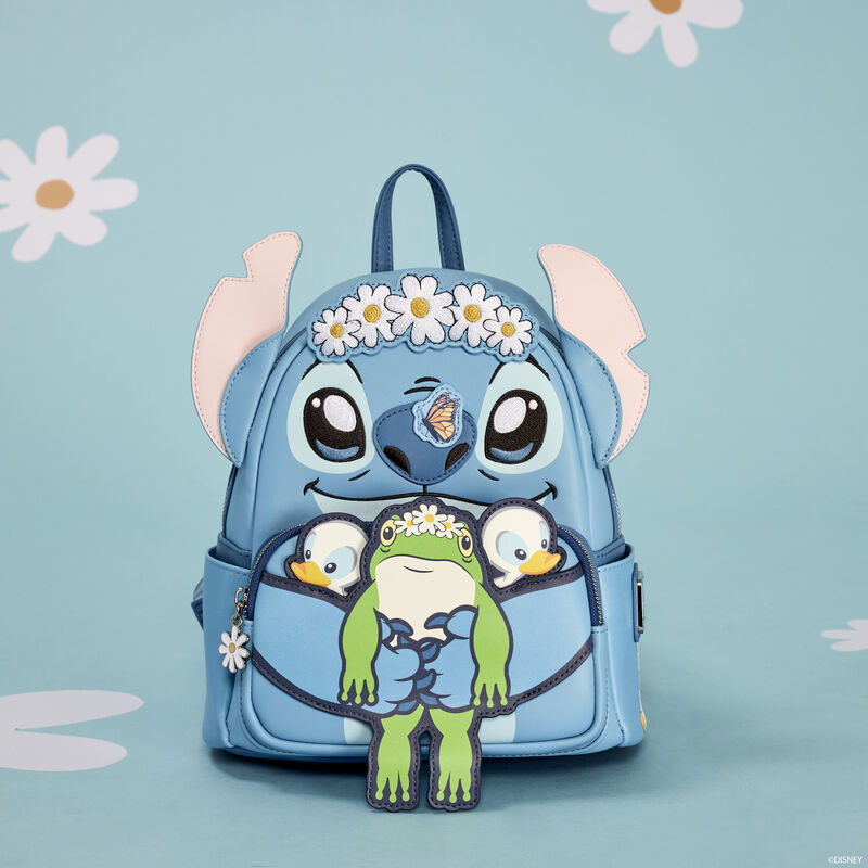 The Lilo & Stitch Springtime Mini Backpack by Blue Dog Posters is an adorable blue accessory crafted from vegan leather. Designed with a playful cartoon character featuring big eyes, ears, and a nose, it showcases the character wearing a daisy flower headband and holding a smaller frog-like figure. The light blue background is adorned with white daisies for added charm.