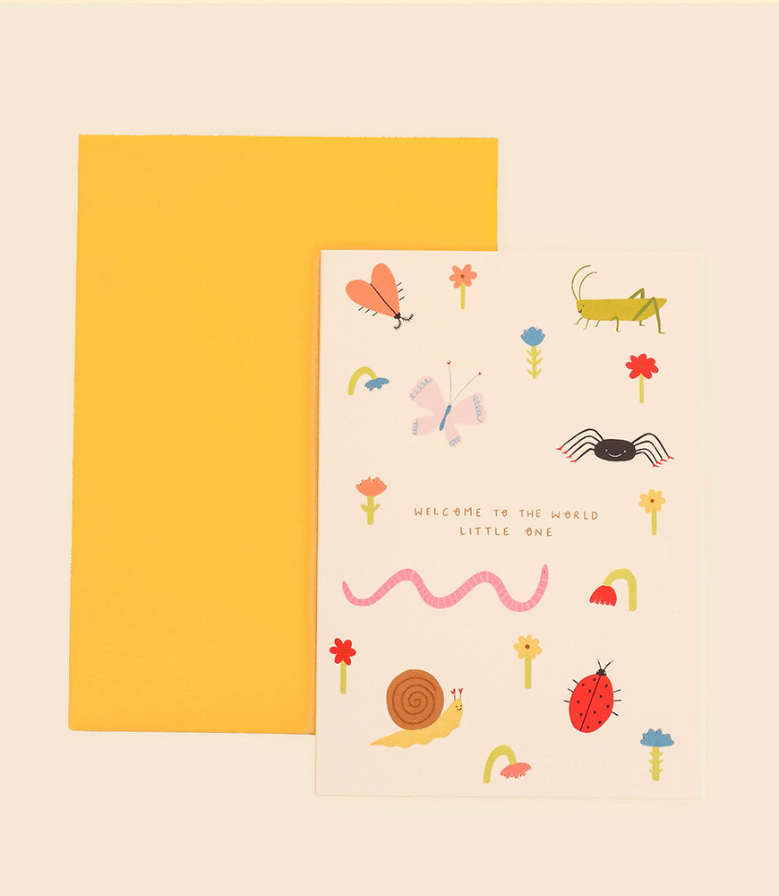 A greeting card named "Welcome to the World Greeting Card" from Blue Dog Posters, comes with a yellow envelope. Designed by Little Black Cat Illustrated in Manchester, UK, it features vibrant drawings of insects, flowers, and a worm surrounding the central message "Welcome to the World Little One.