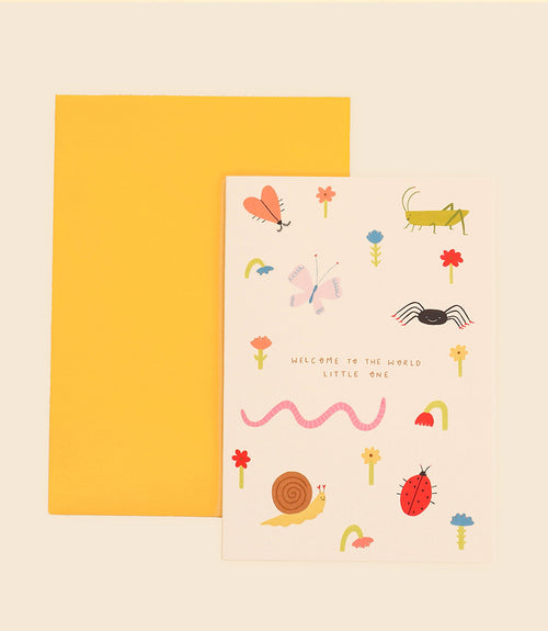 A greeting card named "Welcome to the World Greeting Card" from Blue Dog Posters, comes with a yellow envelope. Designed by Little Black Cat Illustrated in Manchester, UK, it features vibrant drawings of insects, flowers, and a worm surrounding the central message "Welcome to the World Little One.