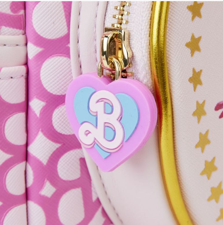 Close-up of a zipper on the Barbie The Movie Logo Mini Backpack by Blue Dog Posters. The zipper pull is a heart-shaped charm with a pink base and blue overlay, featuring a raised letter "B". The bag boasts a pink polka dot pattern and gold detailing, making it perfect for a trip to Barbie Land.