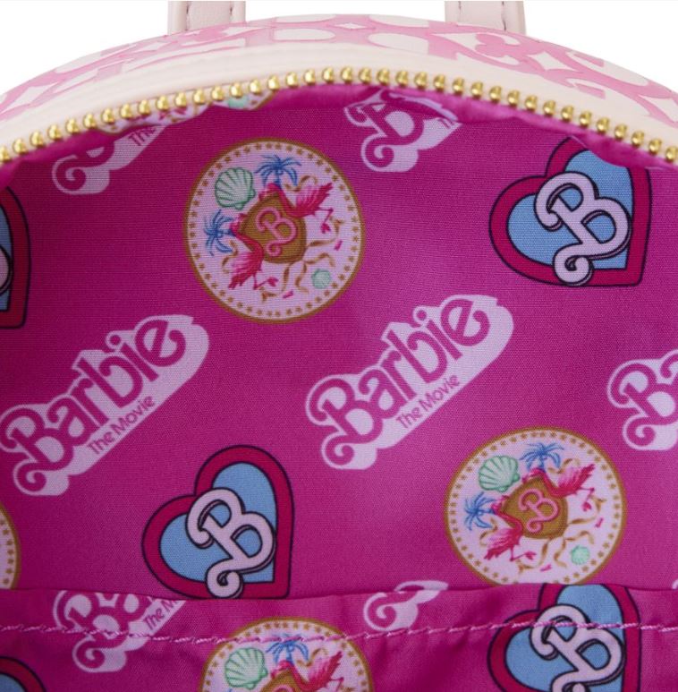 A close-up view of the inside of the Barbie The Movie Logo Mini Backpack from Blue Dog Posters. The interior fabric is pink, showcasing various Barbie logos and designs, such as hearts with a "B" inside, along with decorative roundels featuring pink flamingos and tropical elements. The zipper is gold.