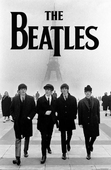 A black-and-white photograph titled "The Beatles Eiffel Tower" from the MUS 161 brand depicts four men walking together in front of the Eiffel Tower on a foggy day. The men, dressed in coats and hats typical of the 1960s, are captured beneath large text that reads "THE BEATLES." This iconic image is a perfect addition to any rock poster collection.