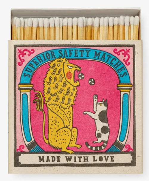 Introducing the Big Cat Little Cat Matchbox by Blue Dog Posters! This matchbox features a charming vintage-style illustration with a yellow lion and a black-and-white cat playing with a ball against a pink background adorned with blue columns. The cover text reads "Superior Safety Matches" and "Made with Love." Inside, you'll find white-tipped, long matches that are perfect for lighting candles.