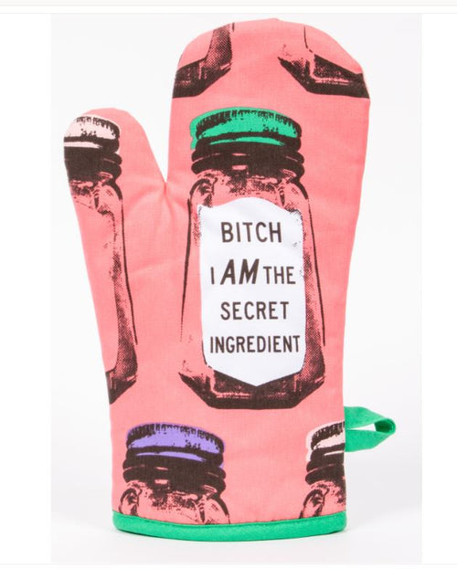 The Oven Mitt - Secret Ingredient by Blue Dog Posters, a colorful, super-insulated 100% cotton mitt with green trim and loop, is displayed against a pink background adorned with salt shaker prints. The mitt prominently features the phrase "BITCH I AM THE SECRET INGREDIENT" in the center.