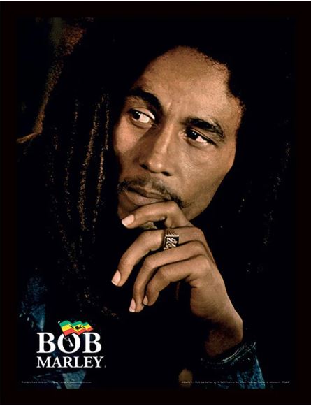 A man with long dreadlocks gazes thoughtfully to the side, wearing a ring on his left hand and holding his hand near his chin. The Bob Marley 30x40cm Mini Poster from Blue Dog Posters is printed on 250gsm satin paper and features text at the bottom that says "Bob Marley." The dark background enhances his contemplative expression in this striking Band mini poster.