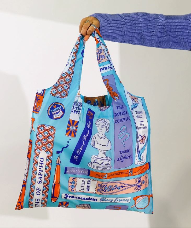 A person with long sleeves is holding a colorful, eco-friendly Bookbag Art Sack by Blue Dog Posters, showcasing various literary-themed designs including book covers, quotes, and illustrations against a white background. Prominent titles featured are "The Divine Comedy" and "Frankenstein." This reusable shopping bag is made from recycled rPet.