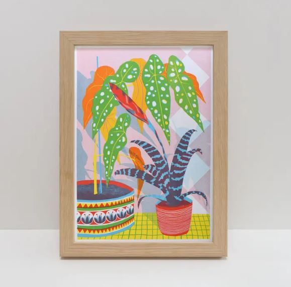 The Bromliad A4 Riso Print by Printer Johnson from Blue Dog Posters showcases framed abstract art of vibrant potted plants with large, patterned leaves set against a geometric pastel background featuring bold greens, blues, reds, and yellows.