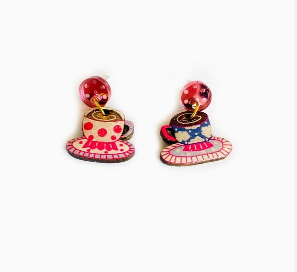 These Coffee Cup Retro Earrings by Blue Dog Posters feature colorful teacup designs with red and blue patterns on matching saucers, complemented by bright pink studs, set against a plain white background.