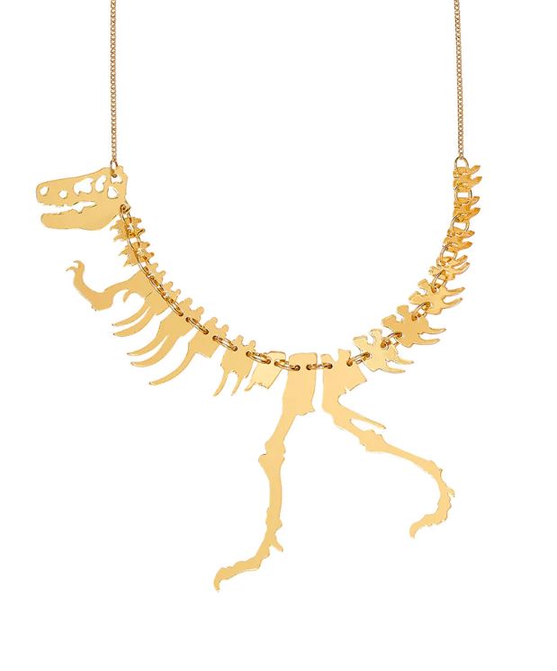Crafted by Blue Dog Posters, the Dinosaur Necklace Gold Colour embodies a Jurassic-inspired design that intricately replicates the skeletal structure of a Tyrannosaurus Rex, featuring a detailed skull, spine, ribs, and legs. This masterpiece is artistically suspended on a delicate chain.