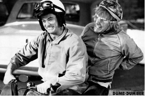 The "Dumb and Dumber Movie Poster" by MTV 011 features two men in helmets and jackets riding a small motorcycle, smiling and laughing in black and white, with a car behind them and the movie title partially visible at the bottom.