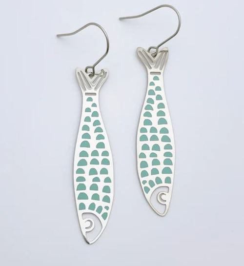 A pair of Blue Dog Posters' Denz Midi Fishy Silver Blue Earrings, featuring elegant aqua blue scale patterns. Lightweight and crafted from recycled stainless steel, these silver earrings showcase a fish design with a cutout tail and head, along with a curved wire hook for easy wearing. The background is plain white.