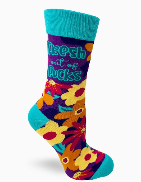 The Fresh Out of Fucks Socks Ladies by Blue Dog Posters are a colorful pair with a teal cuff, heel, and toe. They feature vibrant flowers in shades of yellow, red, and orange set against a purple background, along with teal text that reads "Fresh out of Fucks.