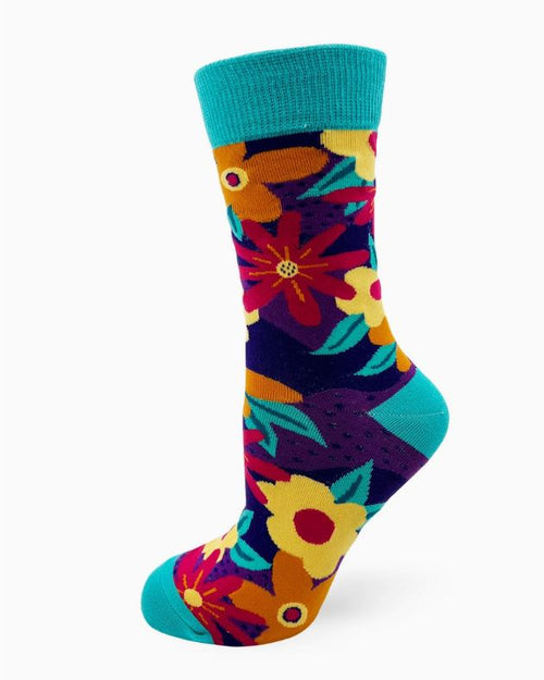 The Fresh Out of Fucks Socks for Ladies by Blue Dog Posters feature a kaleidoscope of vibrant floral patterns in shades of red, yellow, and orange set against a dark blue background. The design is further highlighted by teal accents on the toe, heel, and cuff, providing a striking contrast to the lively pattern. The sock is displayed upright as if worn on a foot.