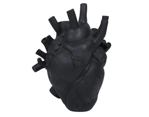 The Anatomical Heart Vase Black from Blue Dog Posters is a realistic, three-dimensional vase crafted in high-quality resin, showcasing detailed structures such as arteries, veins, and chambers. The texture appears smooth, with the heart standing upright and various vessels protruding from it.