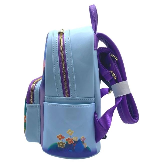 Side view of a small light blue Inside Out Mini Backpack from Blue Dog Posters with purple accents and straps. The backpack features a front pocket and decorative flowers near the bottom. A partially visible character resembling a blue alien peeks out from behind the flowers, adding to its playful charm.