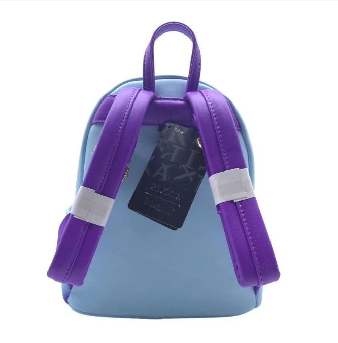 A small light blue Inside Out Mini Backpack from Blue Dog Posters is shown from the back, featuring two padded, bright purple straps. The bag includes a top handle and has a black tag hanging from it.