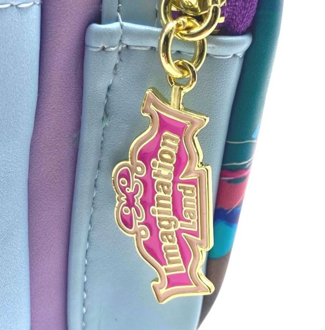 A close-up view of a pastel-colored Blue Dog Posters Inside Out Mini Backpack adorned with a gold and pink keychain. The keychain reads "Imagination Land" in whimsical font. This Disney Pixar backpack showcases light blue, purple, and multicolor floral elements.
